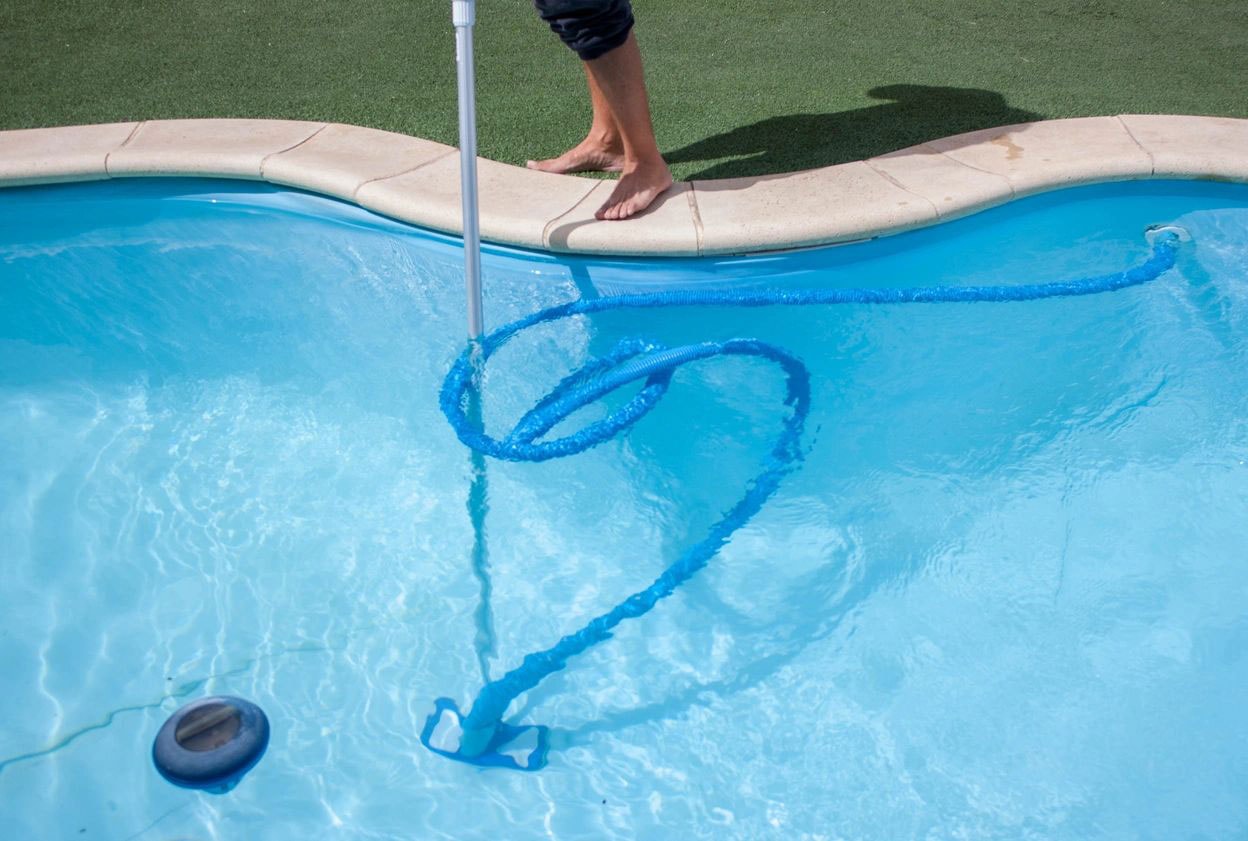 Pool technician cleaning pool with skimmer net